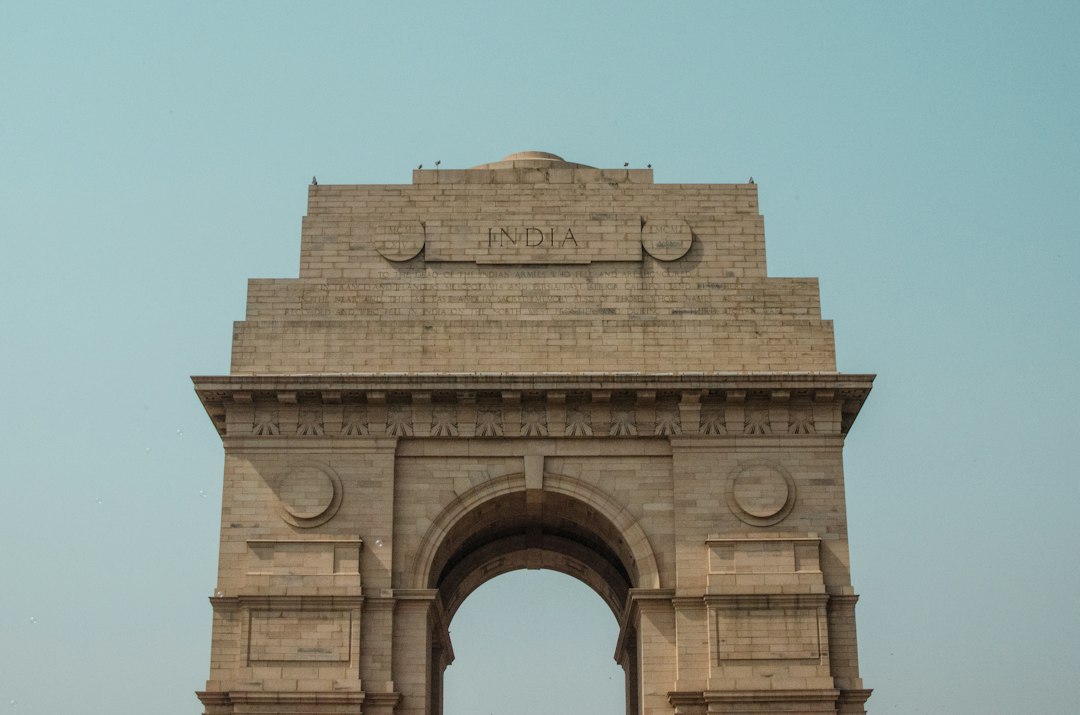 a stone building with a large archway with India Gate in the background